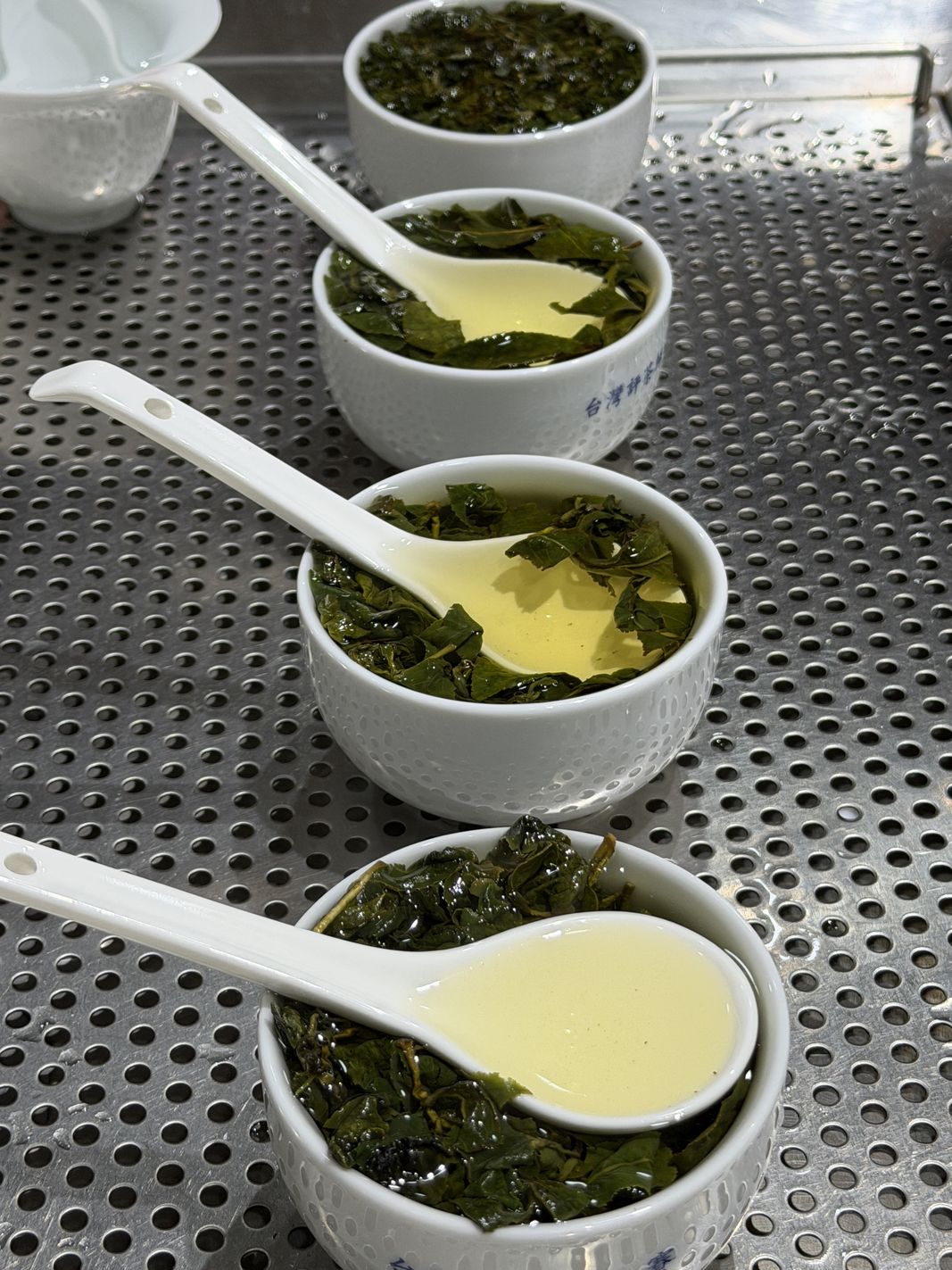 評鑑杯裡舒展的葉底與金黃茶湯,白瓷匙一杯一杯試味
